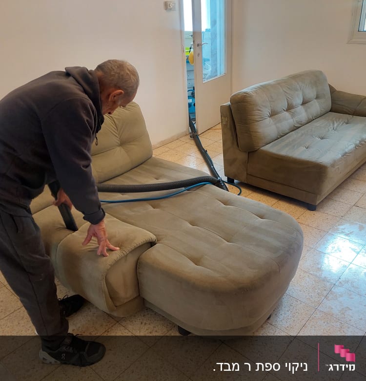 אדם מנקה ספה עם שואב אבק